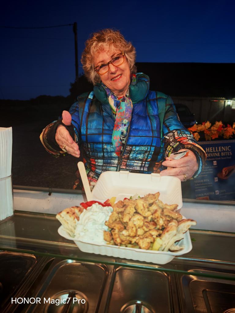 Friendly Hellenic Divine Bites staff member serving authentic Greek food to a customer.