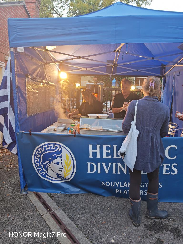 Hellenic Divine Bites branded blue gazebo and street food stall at an outdoor market.