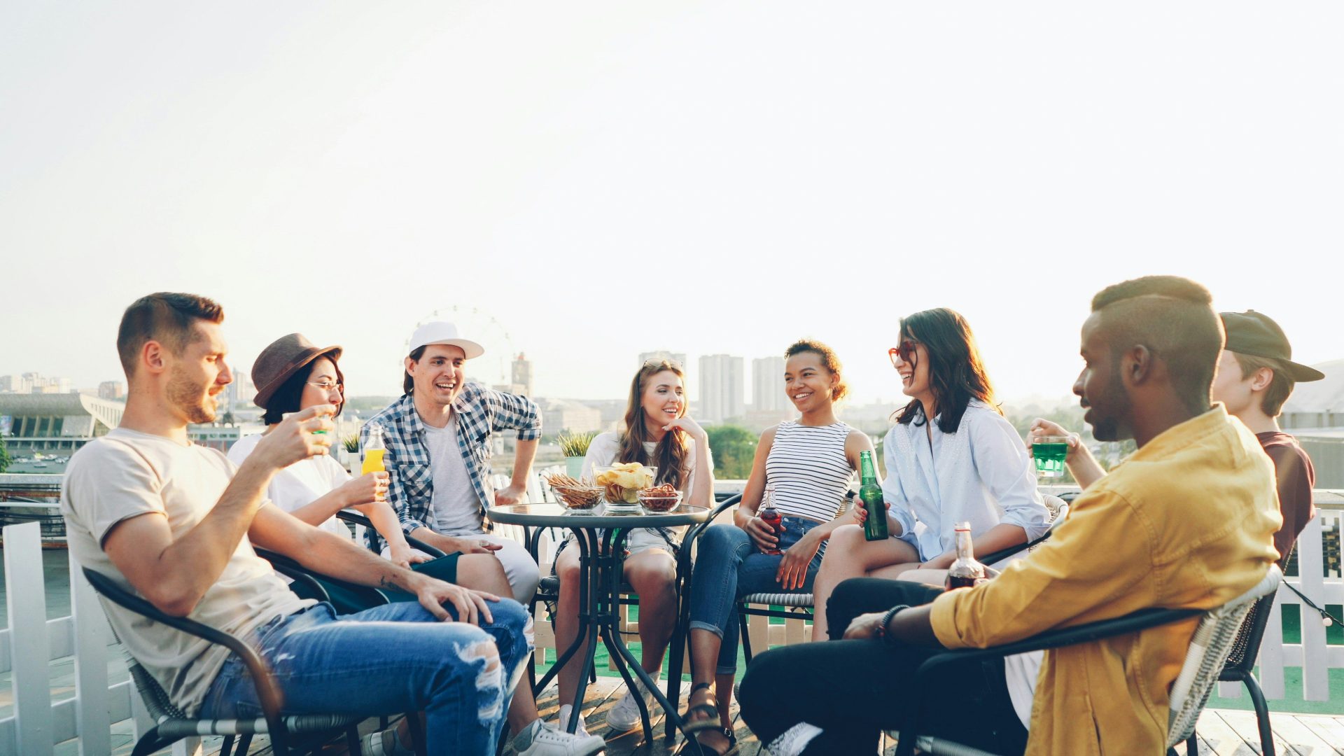 Friends enjoying drinks and snacks on a rooftop.